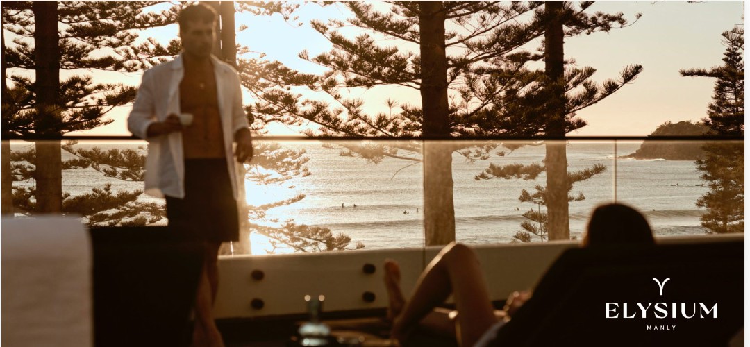 A sunlit balcony at Elysium Manly overlooking the ocean through the Norfolk pines